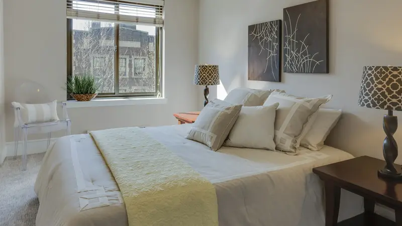 Neatly made bed with cream pillows between two table lamps